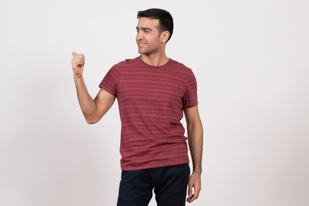 正面図白い背景に笑みを浮かべて立っている暗赤色のTシャツの若い男性