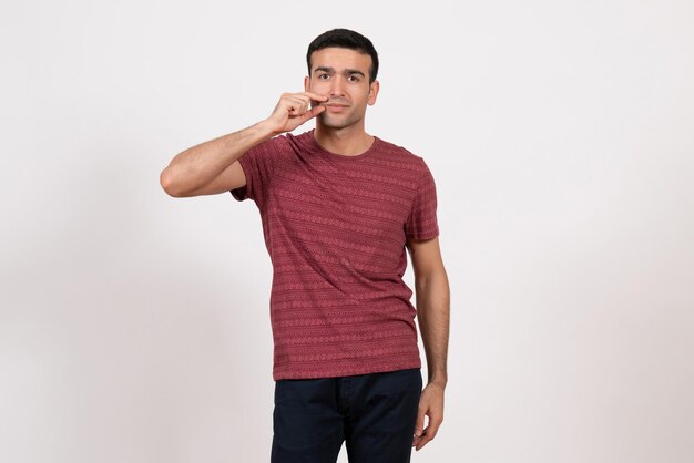 Front view young male in dark-red t-shirt standing on white desk