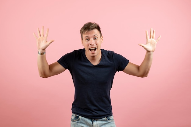 Front view young male in dark t-shirt and jeans posing on a pink background