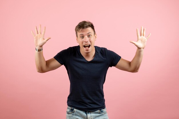 Front view young male in dark t-shirt and jeans posing on a pink background