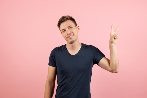 Front view young male in dark t-shirt posing on pink background