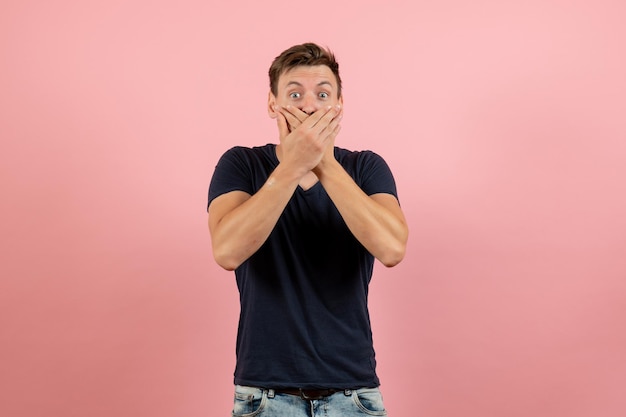 Free photo front view young male in dark t-shirt posing shocked on pink background