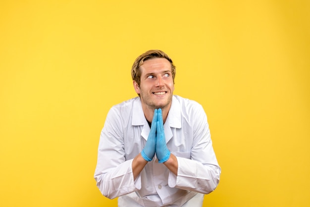 Foto gratuita vista frontale giovane medico maschio eccitato su sfondo giallo medico umano covid-pandemia