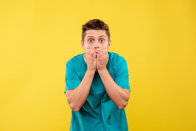 Front view young male doctor in medical suit surprised on yellow background