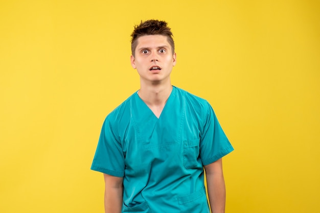 黄色の背景に医療スーツを着た若い男性医師の正面図