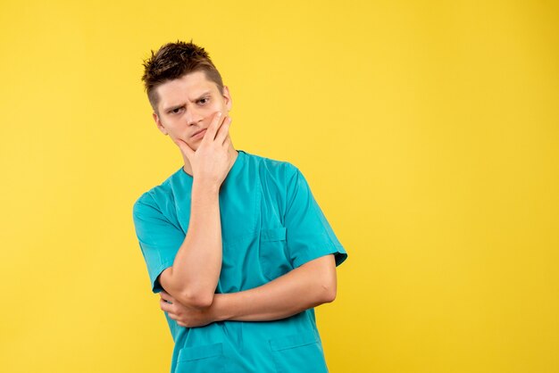 Front view young male doctor in medical suit on yellow background