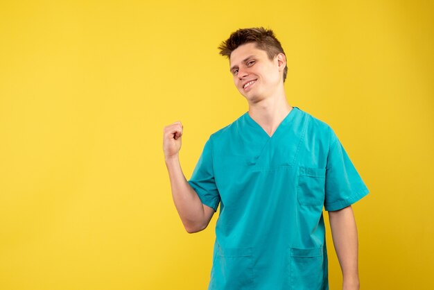 黄色の背景に医療スーツを着た若い男性医師の正面図