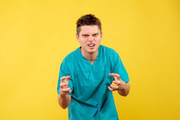 Front view young male doctor in medical suit on yellow background