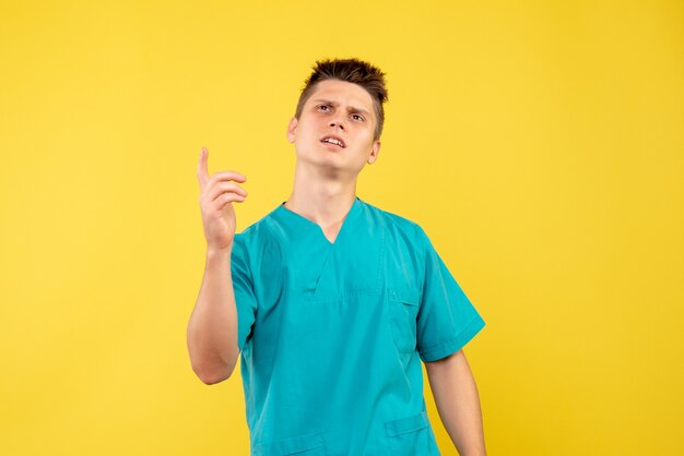 Front view young male doctor in medical suit on the yellow