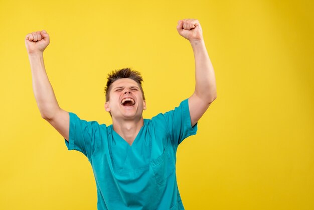 Front view young male doctor in medical suit on yellow