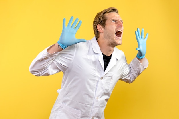 Front view young male doctor screaming on yellow background human covid medic pandemic