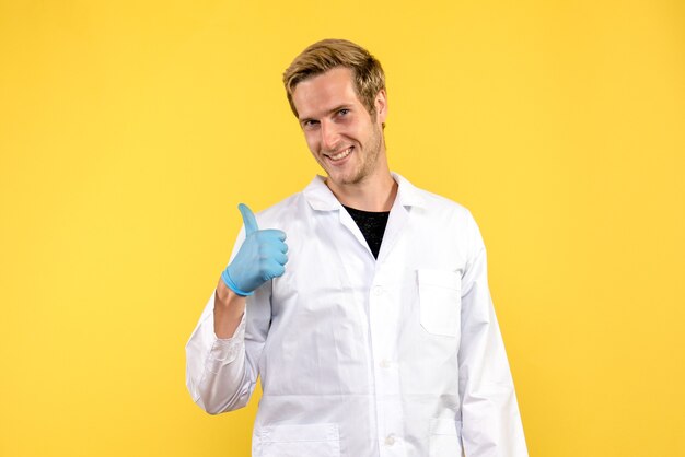 Front view young male doctor smiling on a yellow background human covid medic pandemic