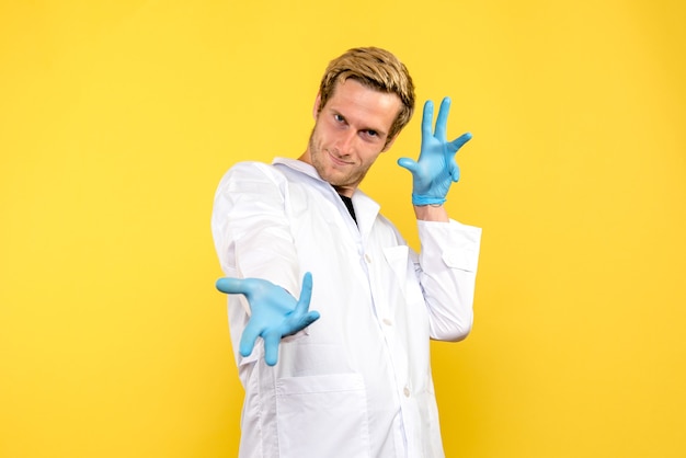 Front view young male doctor smiling on yellow background human covid medic pandemic