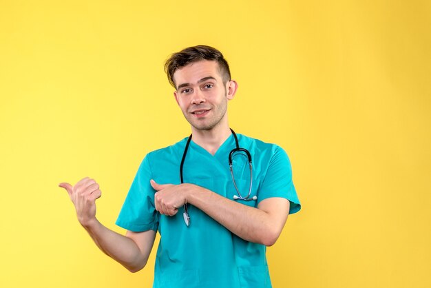 黄色の壁に笑みを浮かべて若い男性医師の正面図