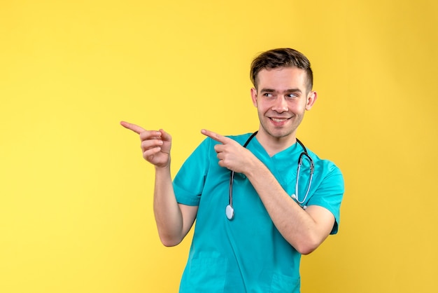 Front view of young male doctor smiling on yellow wall