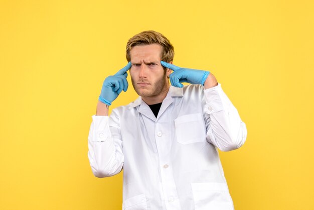 黄色の背景で考える若い男性医師の正面図人間の薬のパンデミック