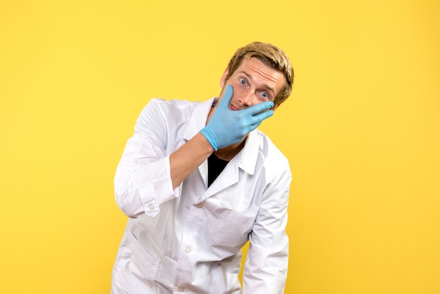 Вид спереди молодой мужчина-врач на желтом фоне пандемия человека covid