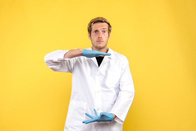 Front view young male doctor on yellow background human medic covid- pandemic