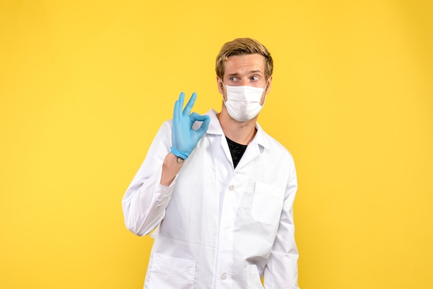 Front view young male doctor on a yellow background pandemic medic health covid-