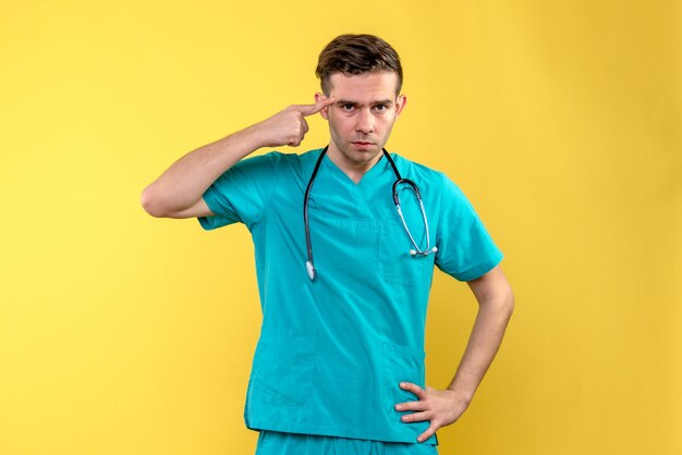 Front view of young male doctor on yellow wall