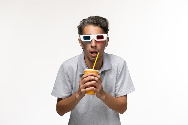 正面図若い男性がソーダを飲み、白い表面にサングラスをかけている