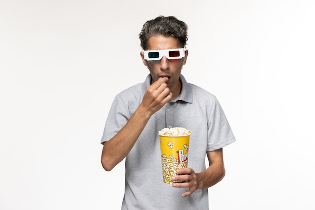 Вид спереди молодой самец ест попкорн в солнцезащитных очках d на белой поверхности