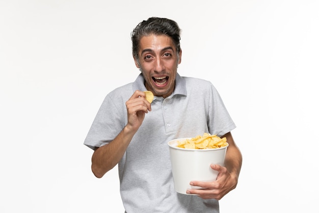 Front view young male eating potato chips and laughing on light white surface