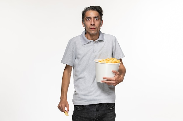 Front view young male eating potato chips on the white surface