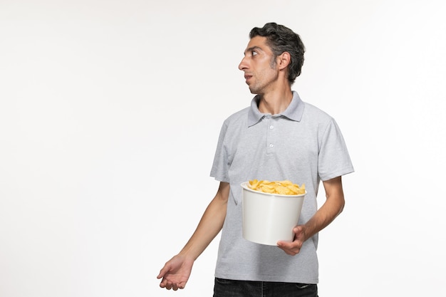 Free photo front view young male eating potato chips on white surface