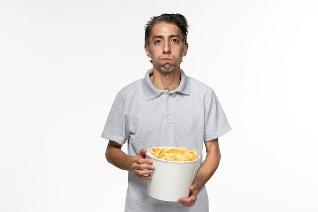 Front view young male eating potato chips on white surface