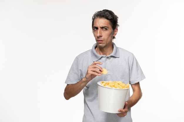 Front view young male eating potato chips on white surface