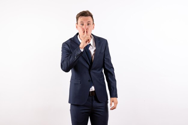 Front view young male in elegant classic suit asking to be silent on white background