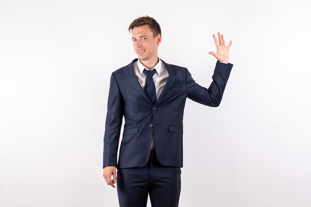 Front view young male in elegant classic suit showing his arm on white background