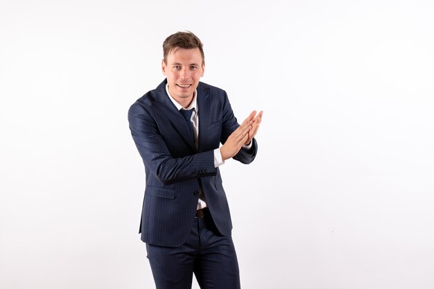 Front view young male in elegant classic suit smiling and clapping on white background