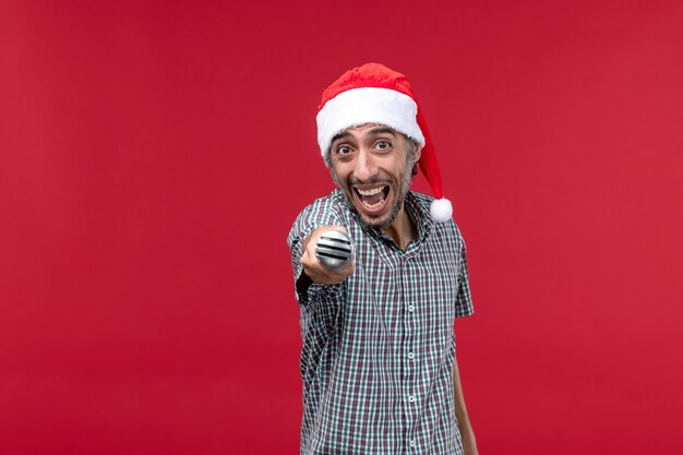 Front view young male emotionally holding mic on red background