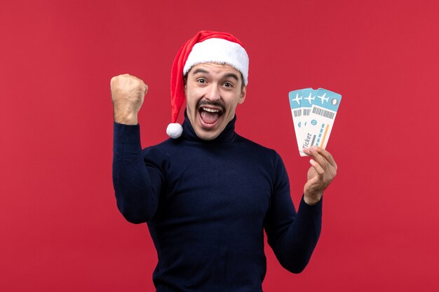 Front view young male emotionally holding tickets on red background