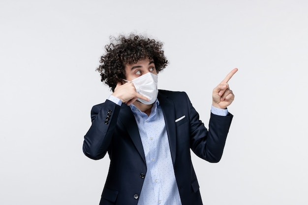 Front view of young male entrepreneur in suit and pointing up on white surface