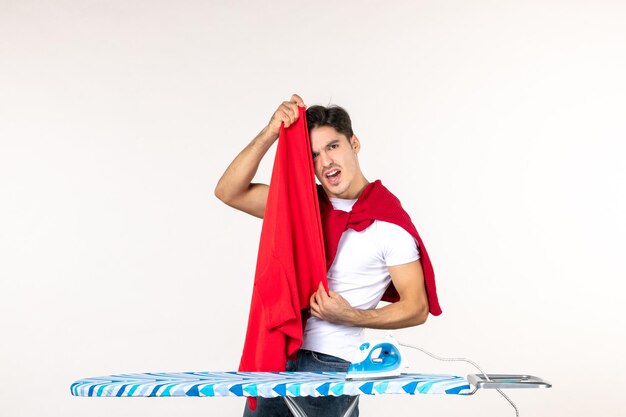 Front view young male folding red towel on the white