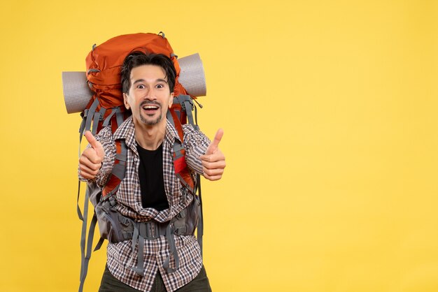 Front view young male going in hiking with backpack delighted on yellow background trip campus height mountain human color tourist