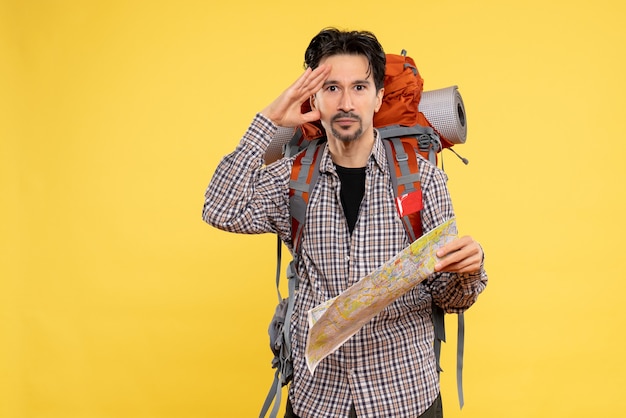 Front view young male going in hiking with backpack holding map on yellow background company trip air nature forest color