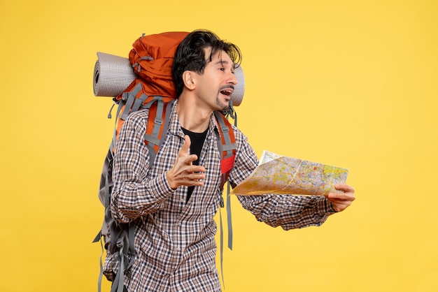 Free photo front view young male going in hiking with backpack observing map on yellow background company trip nature campus forest air