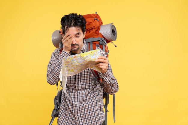 Free photo front view young male going in hiking with backpack observing map on the yellow background company trip nature campus forest color air