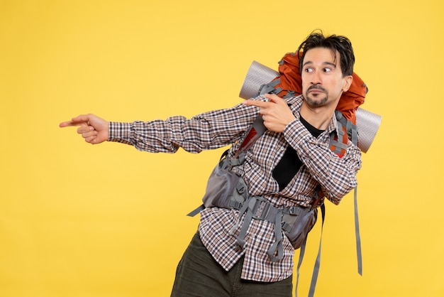 Front view young male going in hiking with backpack on a yellow background color trip campus height human tourist mountain