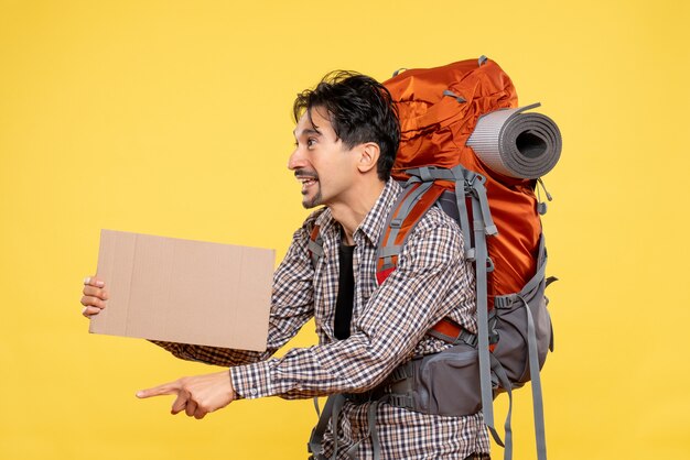 Front view young male going in hiking with backpack on the yellow background map color nature company forest trip campus air