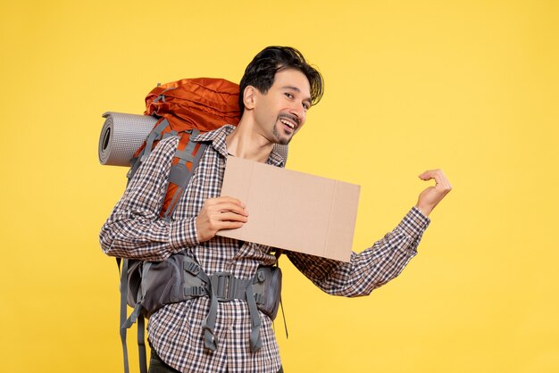 Front view young male going in hiking with backpack on yellow 