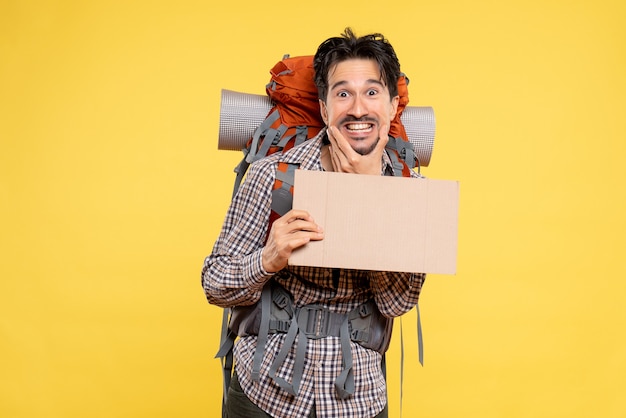 Front view young male going in hiking with backpack on yellow 