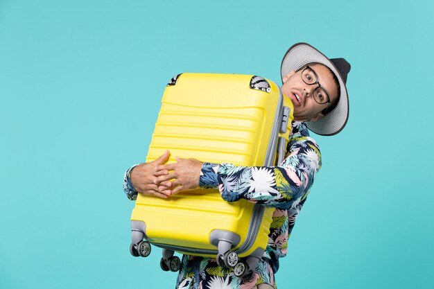 Front view young male going in vacation and holding his bag on light blue space