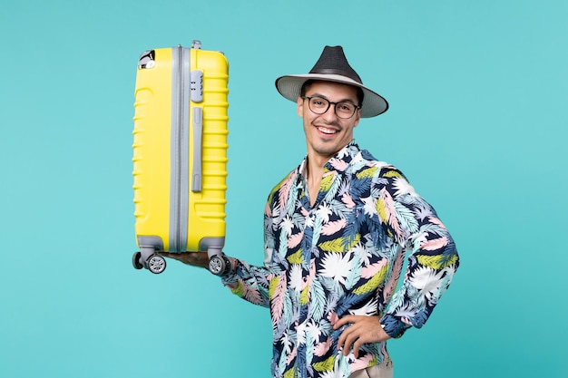 Front view young male going in vacation and holding his yellow bag on blue space