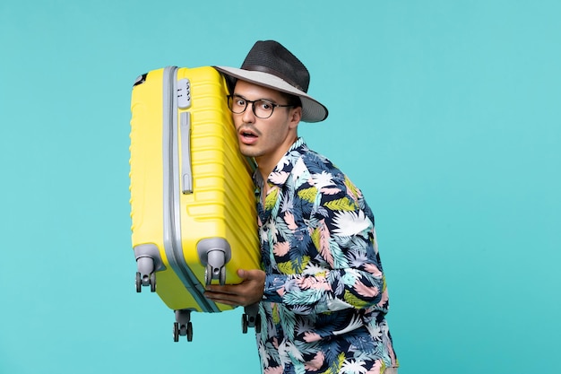 Front view young male going in vacation and holding his yellow bag on light blue space