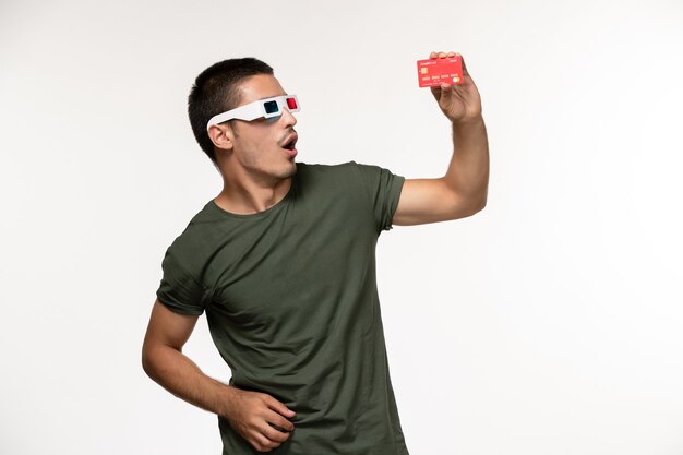 Front view young male in green t-shirt holding bank card in d sunglasses on light white wall film lonely cinema movie